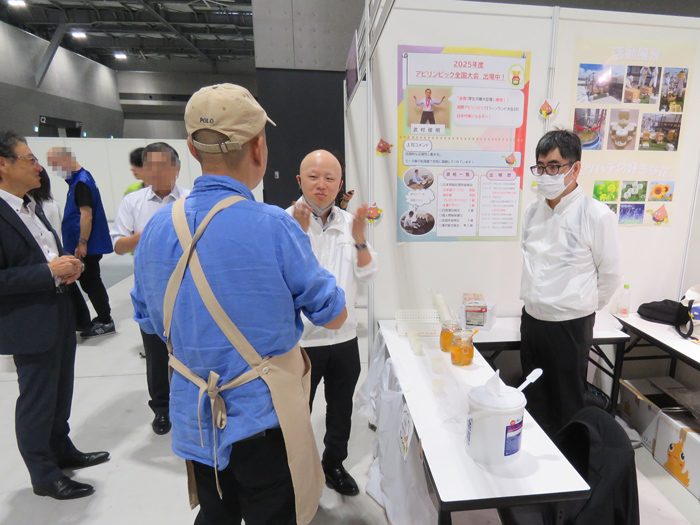 机を囲んで業務改善グッズを見る社員と中学生