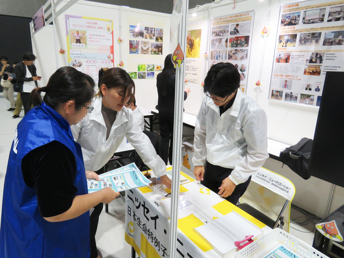 机を囲んで業務改善グッズを見る社員と中学生