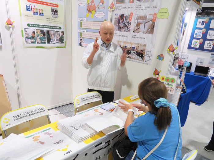 椅子を円形に並べて手話教室を行う社員と中学生